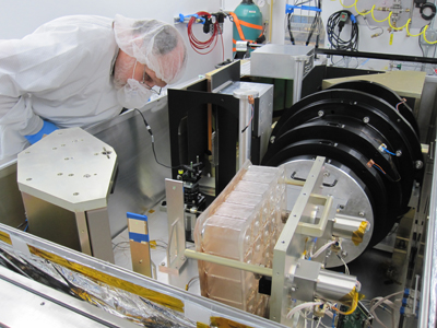 Paul Maseman, wearing a clean suit and mask, examines the APOGEE isntrument